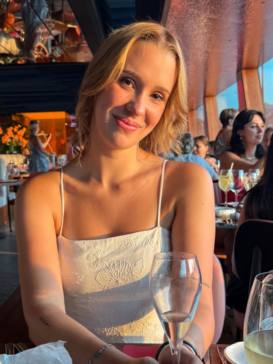 Portrait of Vivi Soter smiling in front of a blush pink wall
